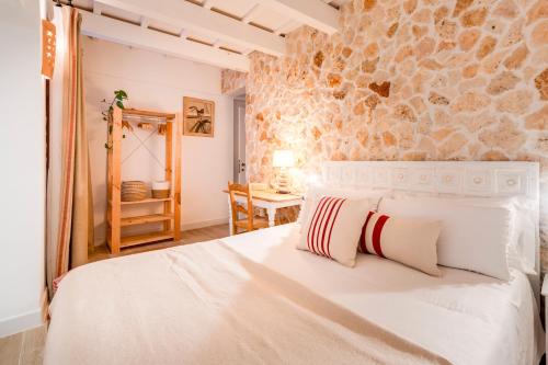 a bedroom with a white bed and a stone wall at Calma Hotel in Ciutadella
