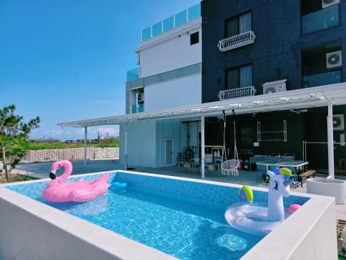 a swimming pool with two inflatable flamingos on a building at 候鳥宜居 宜蘭包棟民宿 in Wujie