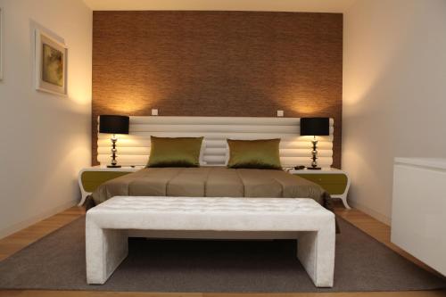 a bedroom with a large bed with a white bench at Hotel Rural Quinta das Quintães in Penafiel
