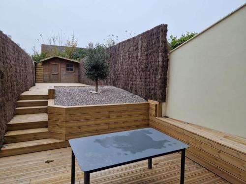 a small patio with a table on a wooden deck at La Maison Elegance & Charme in Marquise