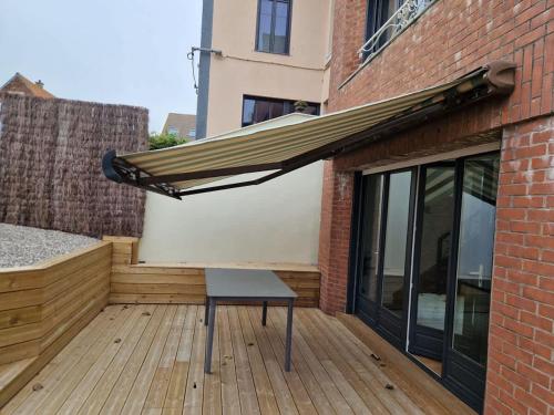a patio with awning and a bench on a deck at La Maison Elegance & Charme in Marquise