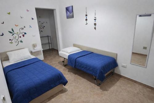 two beds in a room with blue sheets and a mirror at "Babbo" Nicola in Salve
