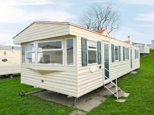 a white tiny house sitting on the grass at Minster - Uk51005 in Eastchurch
