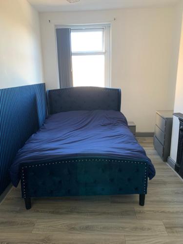 a bedroom with a blue bed with a window at Spacious 5 Bedroom Home Near City Centre Sleeps 10 in Bradford