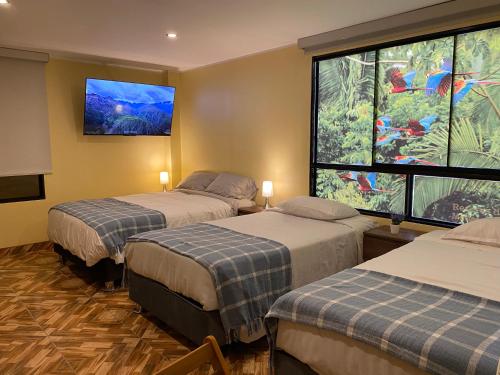 a room with two beds and a large window at Posada Miraflores in Lima