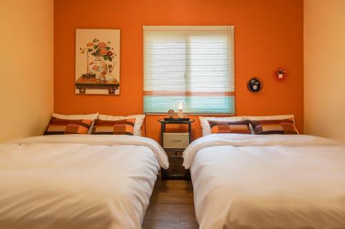 two beds in a room with orange walls at 101STAYㅣFamily-FriendlyㅣStn 1minㅣ2BR 3BedsㅣPrivate Houseㅣ6 GuestsㅣPrivate Yard #DDP #경복궁 #남산 #명동 #홍대 #성수 in Seoul
