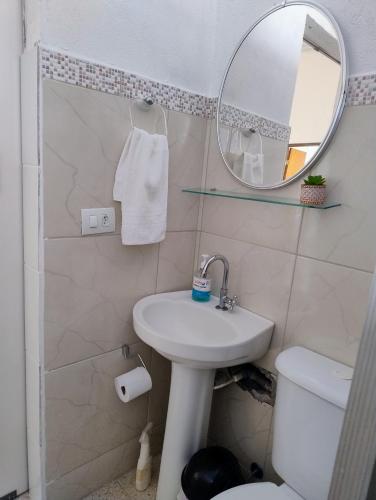 a bathroom with a sink and a mirror and a toilet at Microcasa espaçosa e acolhedora in Caraguatatuba