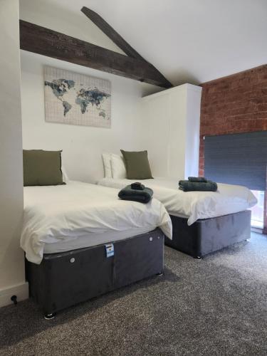 two twin beds in a room with a brick wall at C&B Holdings in Hull