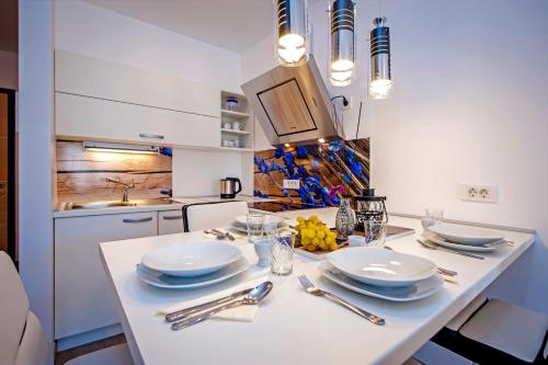 a white kitchen with a table with plates and silverware at Secret Escape in Rovinj