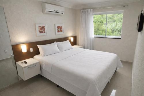 a bedroom with a white bed and a window at 131 - Bombas Summer Beach depto 1 dormitorio para 4 con amenities in Bombinhas
