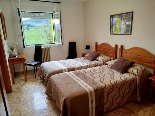 two beds in a room with a window at Posada Gran Sol in Queveda