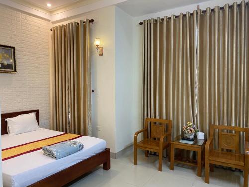 a bedroom with a bed and two chairs and a window at Motel Rose in Hue