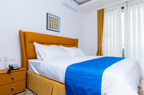 a bedroom with a large bed with a blue blanket at T-Stone Apartments Hotels -Kigali in Kigali