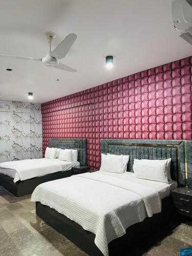two beds in a room with a pink wall at Royal Confort Inn in Karachi