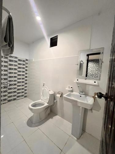 a white bathroom with a toilet and a sink at Royal Confort Inn in Karachi