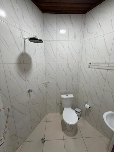 a white bathroom with a toilet and a sink at Casarão Figueiredo in Presidente Figueiredo