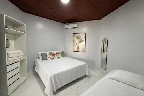 a white bedroom with a bed and a dresser at Casarão Figueiredo in Presidente Figueiredo