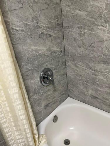 a shower with a white tub in a bathroom at Bragg Motel in Upper Marlboro