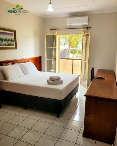 a bedroom with a bed and a desk and a window at Fênix Plaza Hotel in Aquidauana