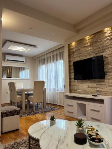ein Wohnzimmer mit einem Tisch und einem Flachbildfernseher in der Unterkunft Apartman MM in Trebinje