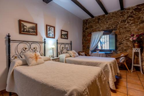 a bedroom with two beds and a stone wall at El Cerrillo in Navaconcejo