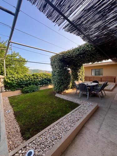 eine Terrasse mit Tisch und Stühlen unter einer Pergola in der Unterkunft Apartman MM in Trebinje