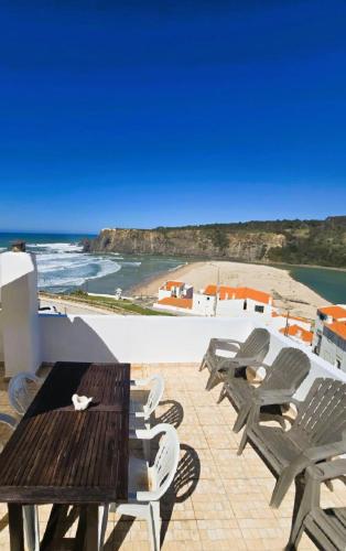 a patio with a table and chairs and a beach at Sol da Praia in Odeceixe