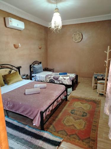 a bedroom with two beds and a chandelier at Auberge Restaurant TISSILI " Oasis de Fint" in Fint