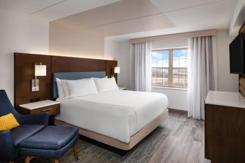 a bedroom with a large white bed and a chair at EVEN Hotel Chicago - Tinley Park - Convention Center by IHG in Tinley Park