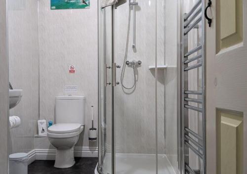 a bathroom with a toilet and a glass shower at Kingswinford Guest House with Free Parking in Paignton