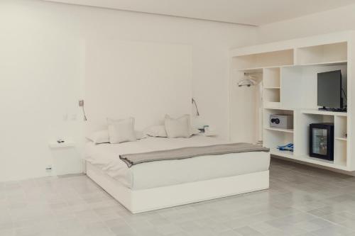 a white bedroom with a white bed and a tv at Hotel Azul de Oaxaca in Oaxaca City