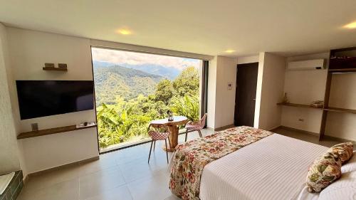 a bedroom with a large window with a bed and a table at Hotel El Mirador del Cocora in Salento