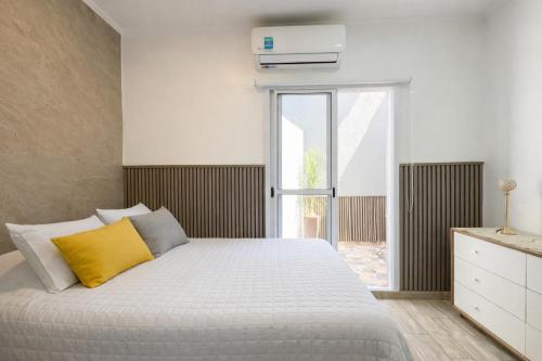 a bedroom with a white bed with a yellow pillow at Departamento Moderno, equipado en Vicente Lopez , Ideal River Plate ,Tecnópolis ,100 metros del tren in Vicente López