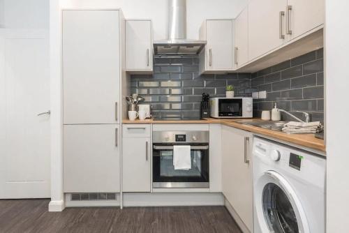 a kitchen with white cabinets and a washer and dryer at Cosy 1 Bedroom Apartment in Bradford in Bradford