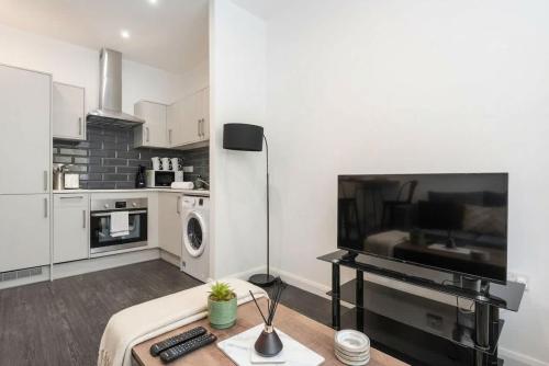 a white living room with a tv and a kitchen at Cosy 1 Bedroom Apartment in Bradford in Bradford