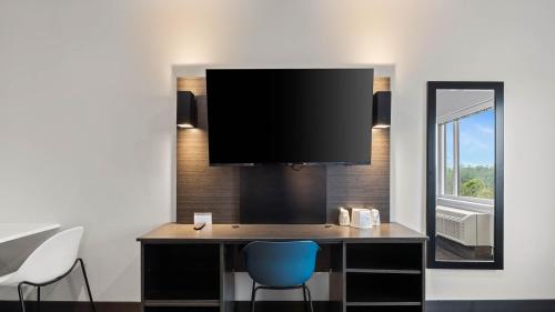 a room with a desk with a tv on a wall at Studio 6 Richmond, VA - Airport in Sandston
