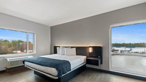 a bedroom with a bed and two large windows at Studio 6 Richmond, VA - Airport in Sandston