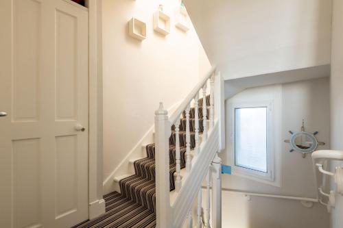 a white staircase in a home with white walls at Harbour View - Anstruther in Anstruther