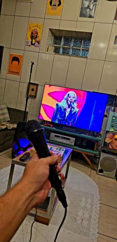 a person holding a video game controller in front of a tv at Carcará Hostel Ipanema - Zona Sul POA in Porto Alegre