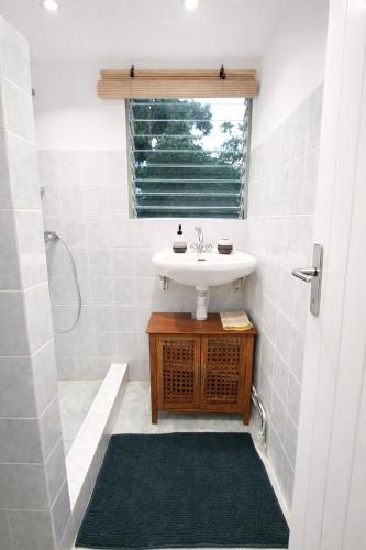 a white bathroom with a sink and a shower at Studio Anthurium in Gros-Morne