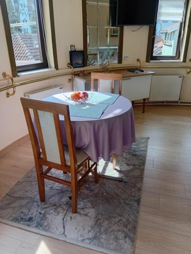a table with a purple table cloth and two chairs at Studio Carobna Dunja in Banja Koviljača