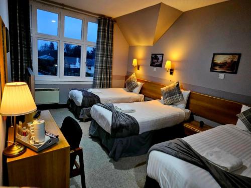 a hotel room with three beds and a window at St Michaels Hotel in St. Michaels