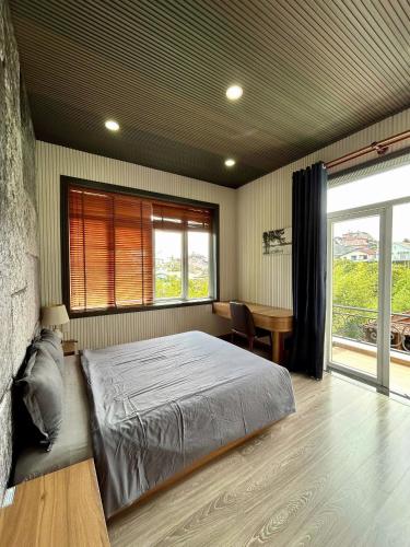 a bedroom with a bed and a desk and a window at Twins Villa Đà Lạt in Khu Chi Lăng