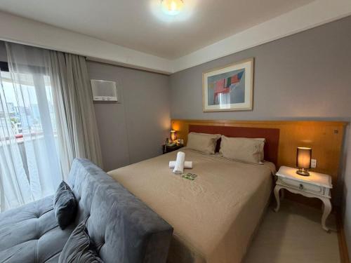 a bedroom with a bed and a couch and a window at Hotel Flat Biena Parque Ibirapuera 1101 incluso estacionamento in São Paulo