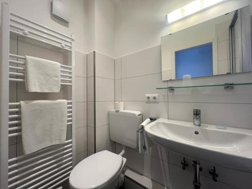 a white bathroom with a toilet and a sink at Hotel an der Hauptallee in Bad Pyrmont