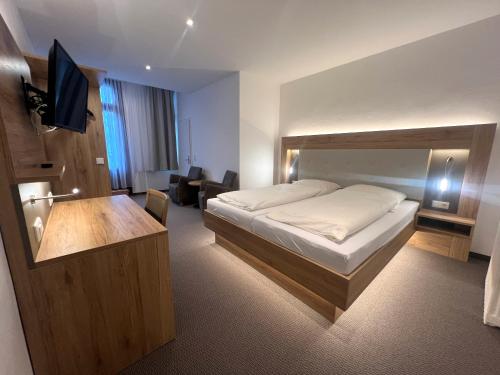 a bedroom with a bed and a desk with a television at Hotel an der Hauptallee in Bad Pyrmont