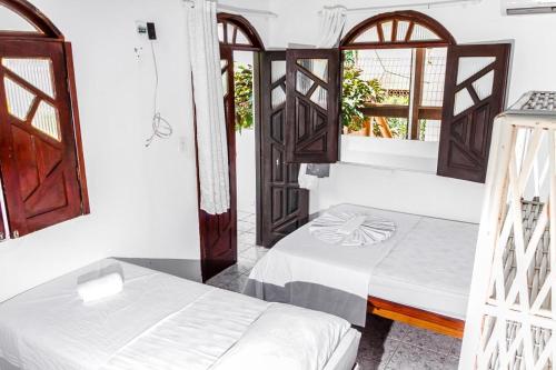 a room with two beds and two windows at Pousada Sol E Mar in Morro de São Paulo