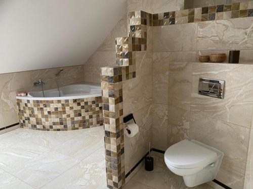 a bathroom with a toilet and a bath tub at Mirabelka Mucharz in Mucharz