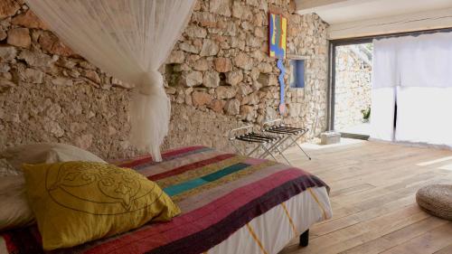 a bedroom with a bed and a stone wall at Maison Nomade Provence - MaisonNomadeChic in Coursegoules