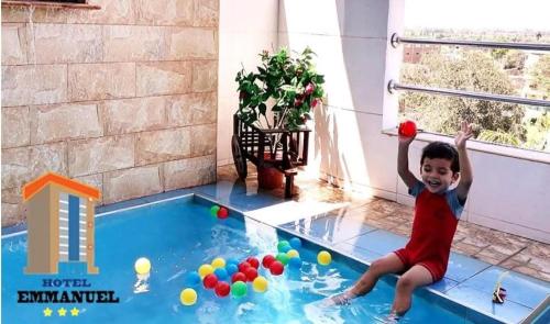 a young boy playing with balls in a swimming pool at Hotel Emmanuel in Chepén